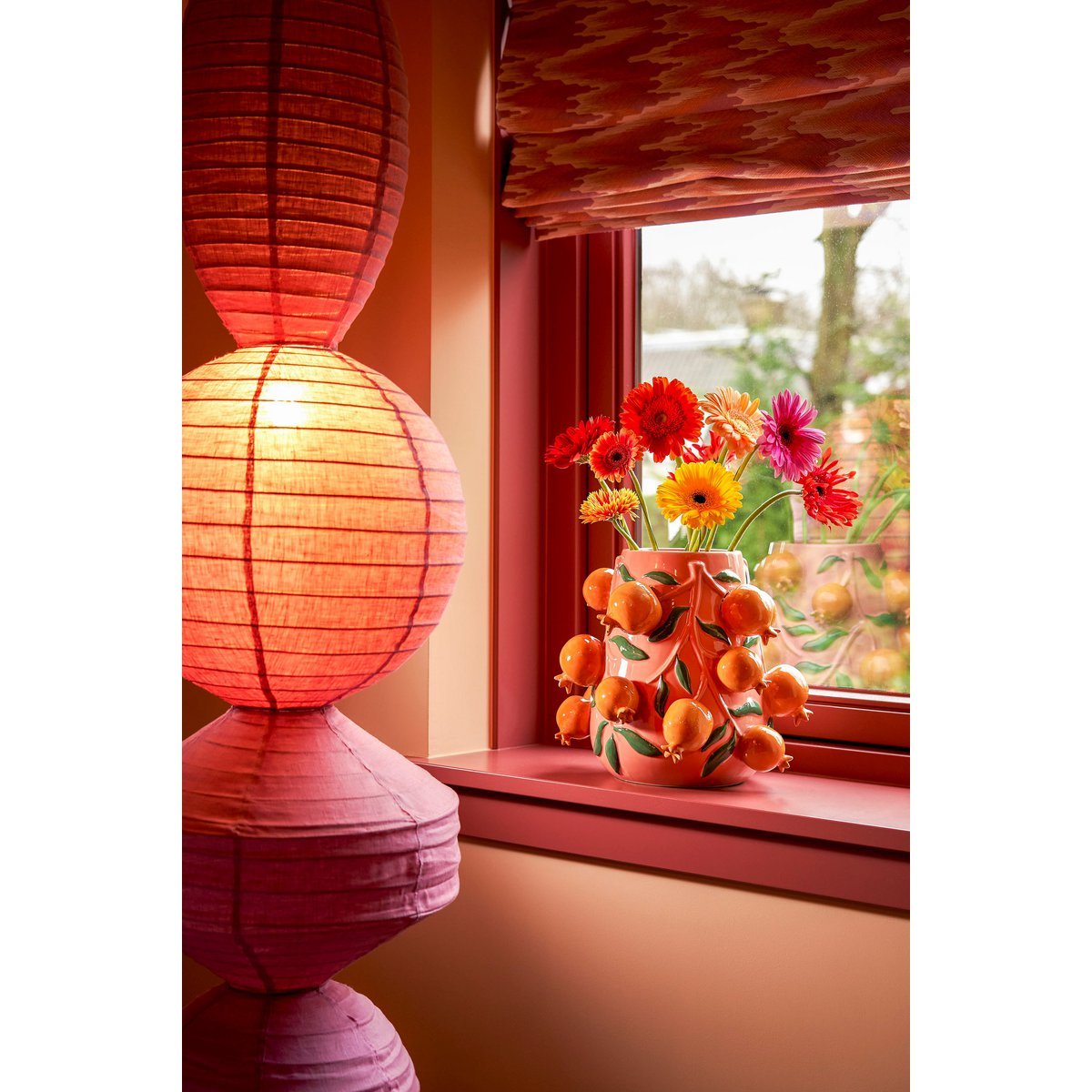 Gekleurde vaas met fruit eraan in vensterbank